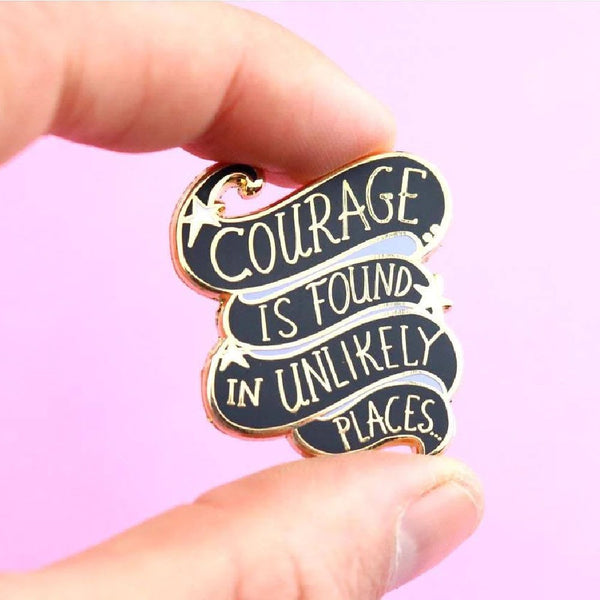 JUBLY-UMPH-Courage-Is-Found-In-Unlikely-Places-Lapel-Pin-between-fingers