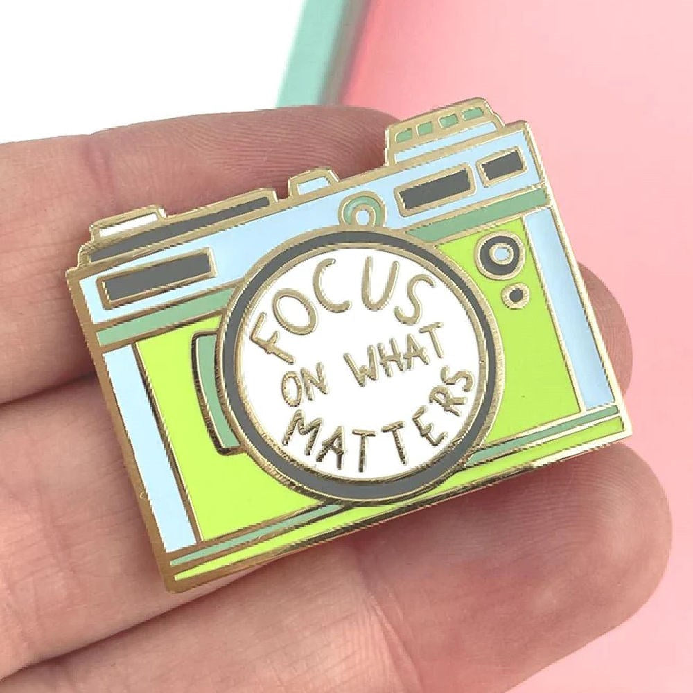 JUBLY-UMPH-Focus-On-What-Matters-Lapel-Pin-On-Fingers
